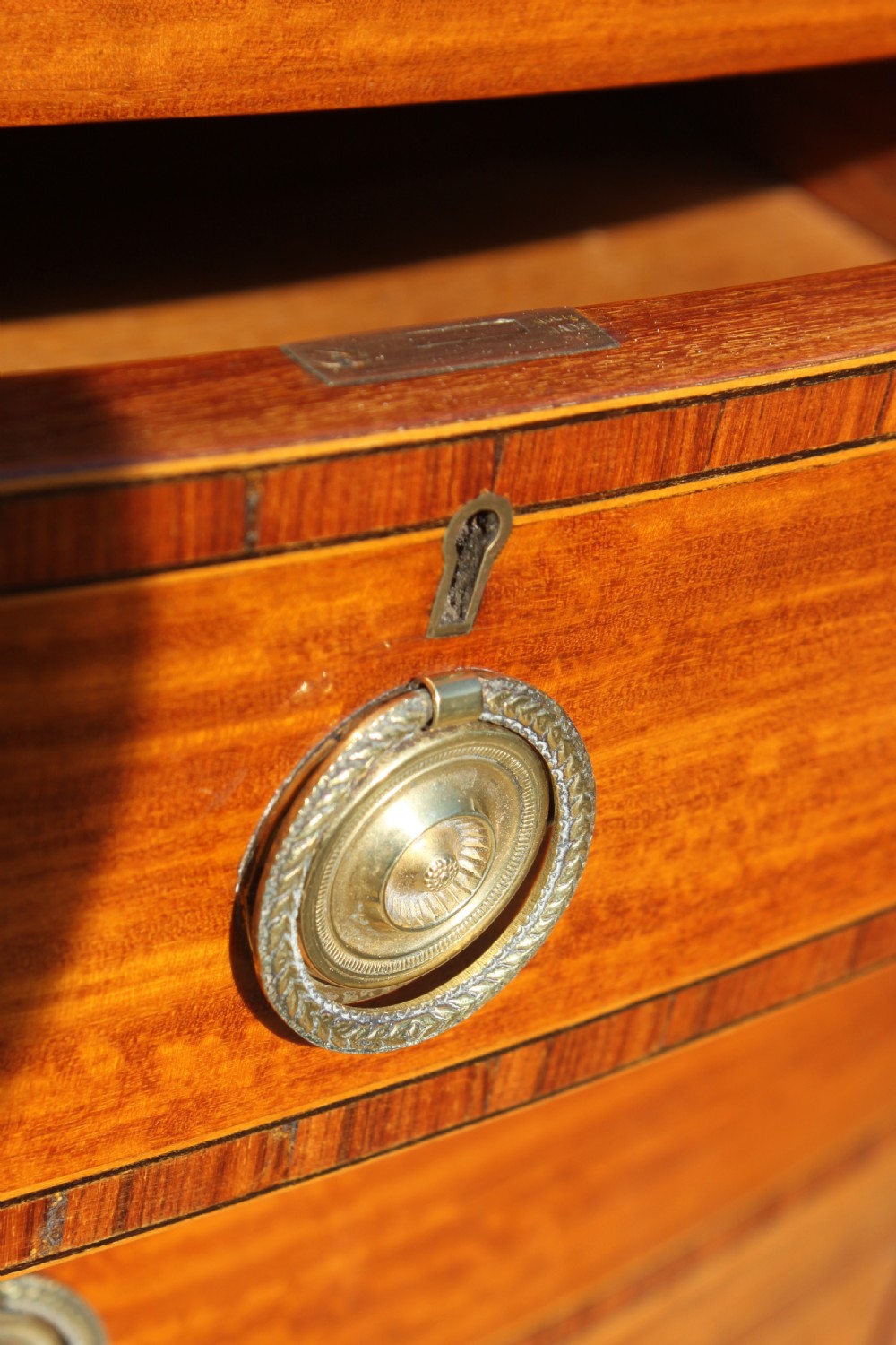 A tall Sheraton Revival satinwood bow front chest featuring six drawers with inlaid crossbanded borders, central brass ring handles, and splayed bracket feet. View VIII