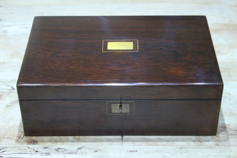 A rectangular dark rosewood writing slope box featuring a central brass cartouche and key inserted in the front lock. View II