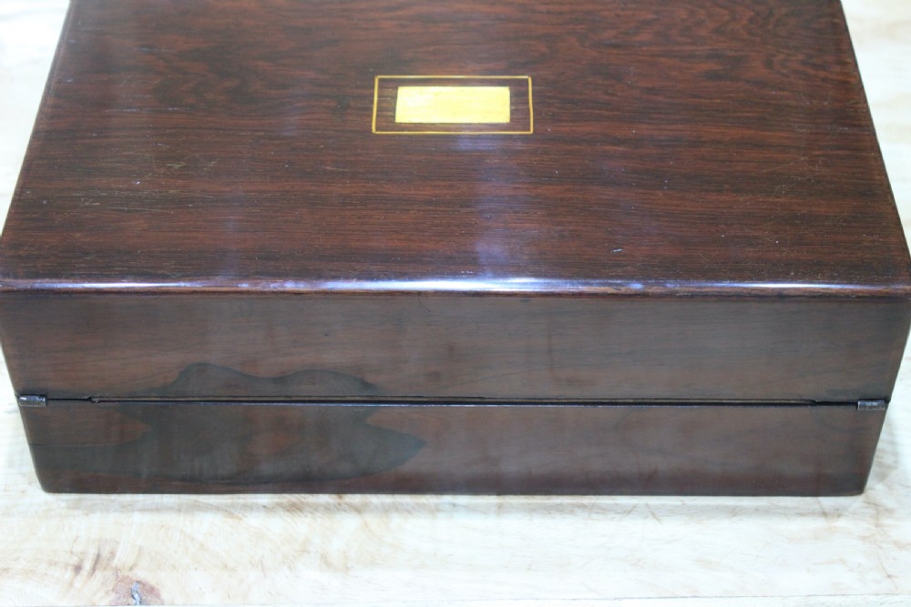 A rectangular dark rosewood writing slope box featuring a central brass cartouche and key inserted in the front lock. View III