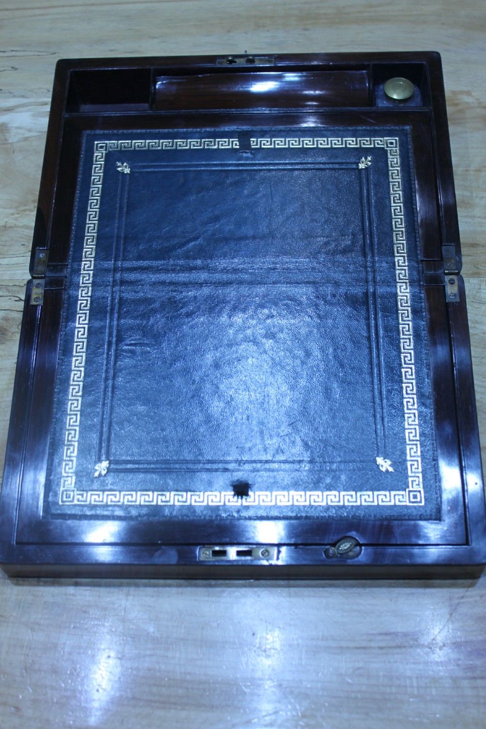A rectangular dark rosewood writing slope box featuring a central brass cartouche and key inserted in the front lock. View XV