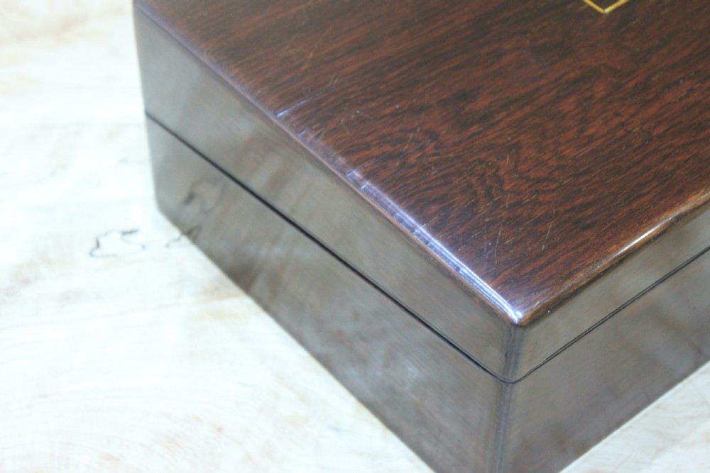 A rectangular dark rosewood writing slope box featuring a central brass cartouche and key inserted in the front lock. View XVII