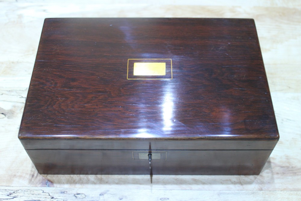 A rectangular dark rosewood writing slope box featuring a central brass cartouche and key inserted in the front lock. View XX