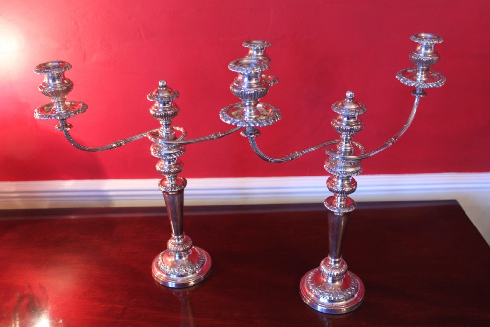 A pair of silver-plated three-light candelabra featuring classical turned column stems, gadrooned borders, and twin curved branches. View X
