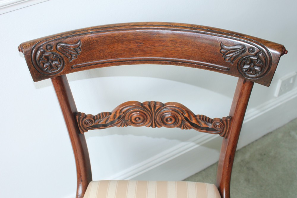 A set of six dark mahogany Regency dining chairs featuring carved top rails, reeded front legs, and cream striped fabric seats. View III