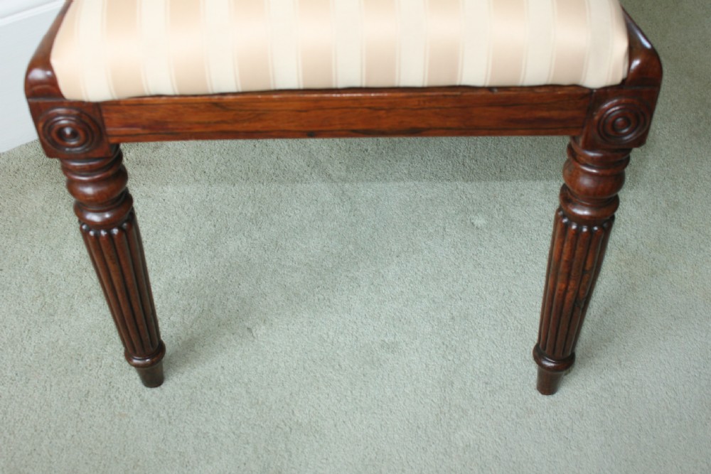 A set of six dark mahogany Regency dining chairs featuring carved top rails, reeded front legs, and cream striped fabric seats. View VI