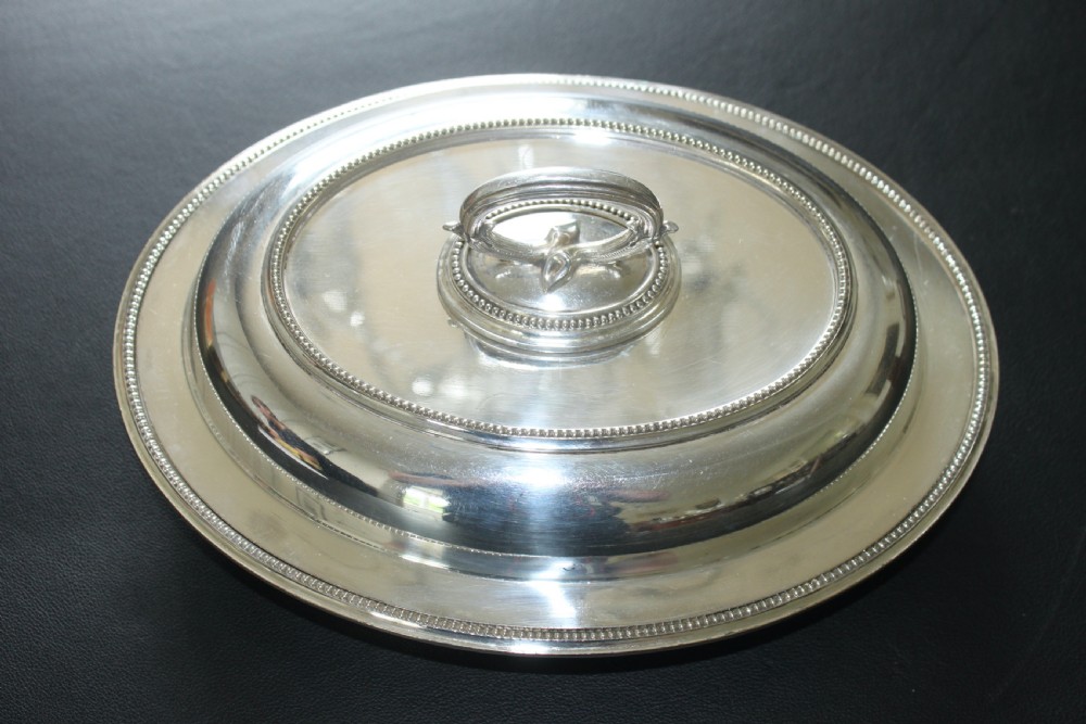 An oval Edwardian silver-plated entree dish featuring a beaded border and a central loop handle.