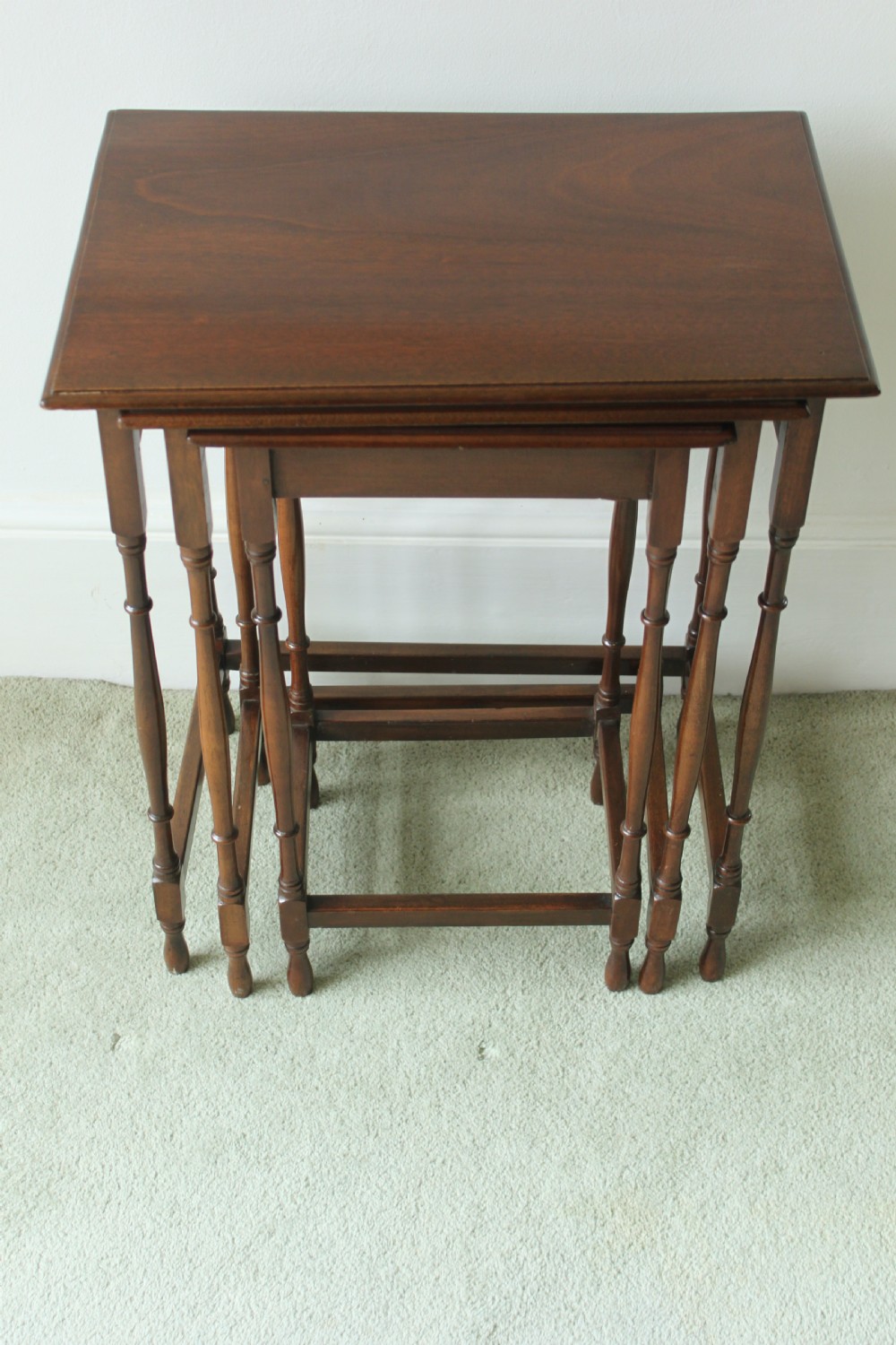 A set of three graduated mahogany Edwardian nesting tables with turned legs standing nested together.