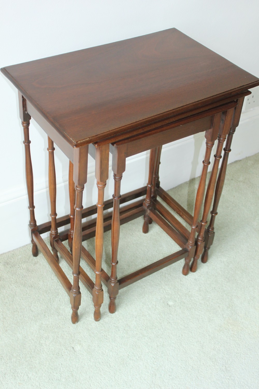 A set of three graduated mahogany Edwardian nesting tables with turned legs standing nested together. View II