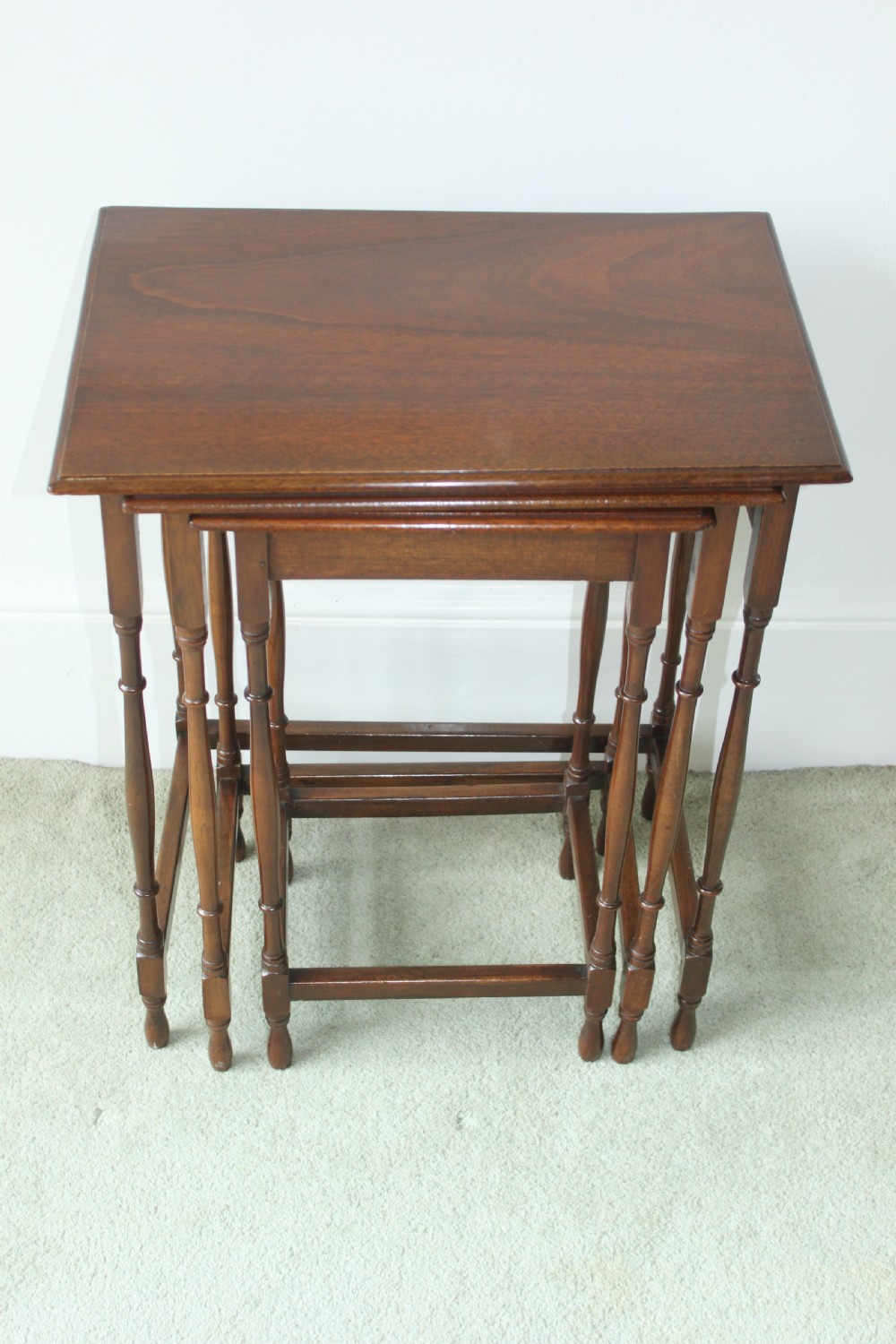 A set of three graduated mahogany Edwardian nesting tables with turned legs standing nested together. View III