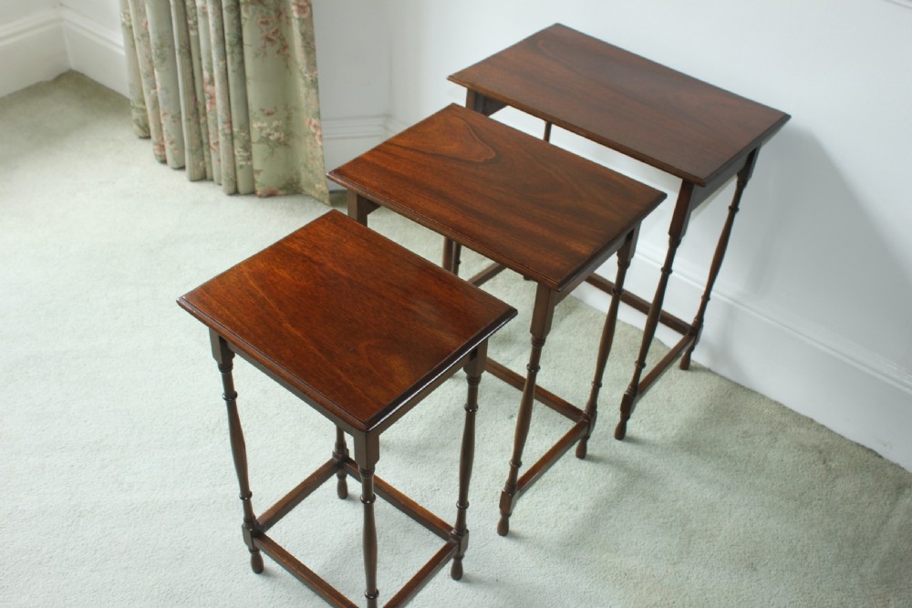A set of three graduated mahogany Edwardian nesting tables with turned legs standing nested together. View VI