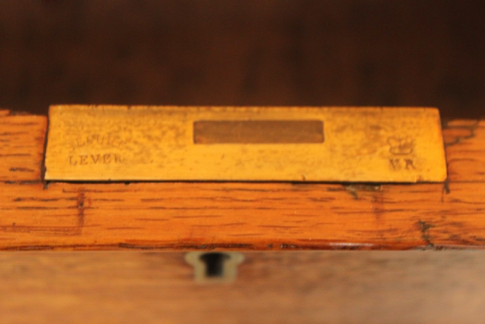 A 19th-century oak pedestal desk featuring a dark green leather writing surface with gold tool gilding, nine drawers with turned wooden knobs, and decorative carved kneehole spandrels. View XII