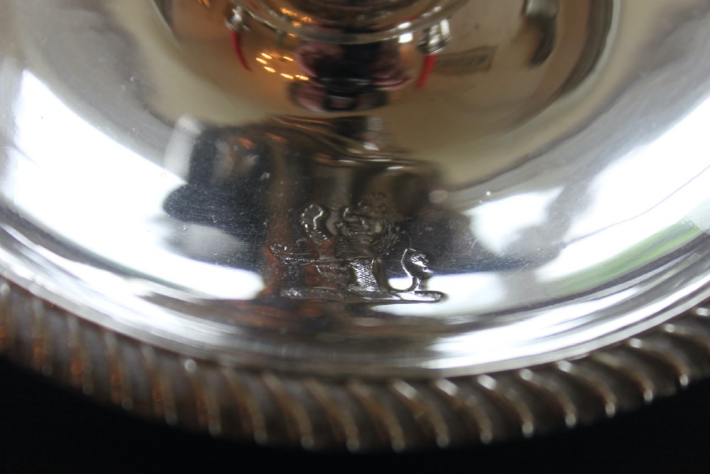 A set of four early nineteenth-century silver-plated chambersticks with circular drip pans, gadrooned rims, curved handles, and conical extinguishing snuffers. View II