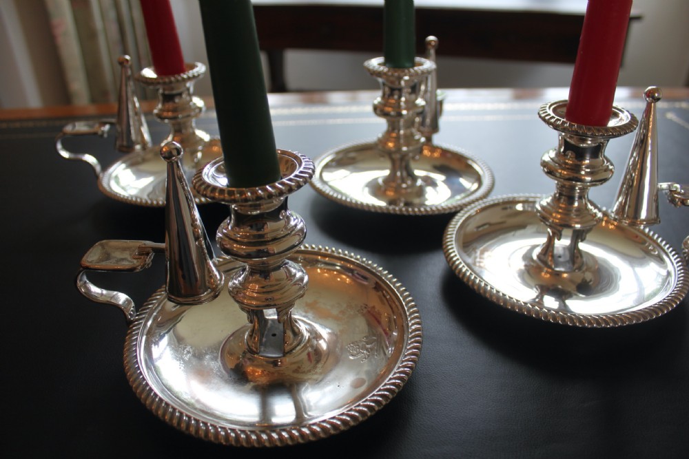 A set of four early nineteenth-century silver-plated chambersticks with circular drip pans, gadrooned rims, curved handles, and conical extinguishing snuffers. View III