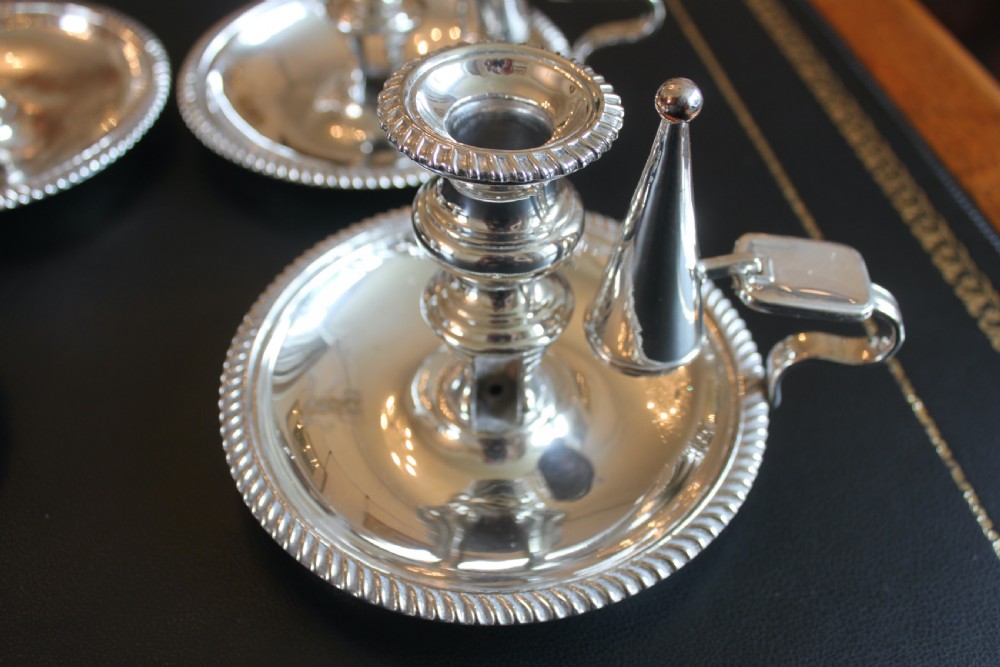 A set of four early nineteenth-century silver-plated chambersticks with circular drip pans, gadrooned rims, curved handles, and conical extinguishing snuffers. View VI