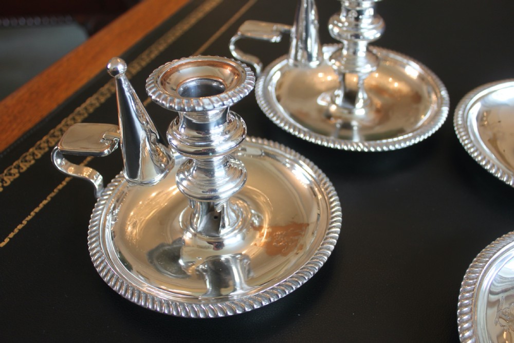 A set of four early nineteenth-century silver-plated chambersticks with circular drip pans, gadrooned rims, curved handles, and conical extinguishing snuffers. View VII