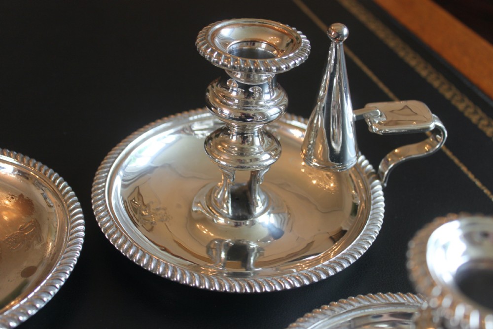 A set of four early nineteenth-century silver-plated chambersticks with circular drip pans, gadrooned rims, curved handles, and conical extinguishing snuffers. View IX