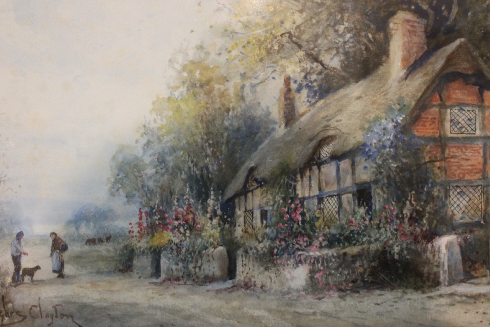 A framed watercolour painting depicting a thatched cottage alongside a country lane with figures, housed within a cream mount and an ornate swept gold frame. View VII