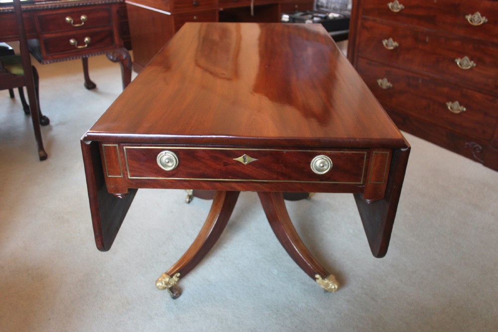 A dark mahogany Regency Pembroke table featuring brass line inlay, a single end drawer, drop leaves, and quadform sabre legs with brass cap castors. View II