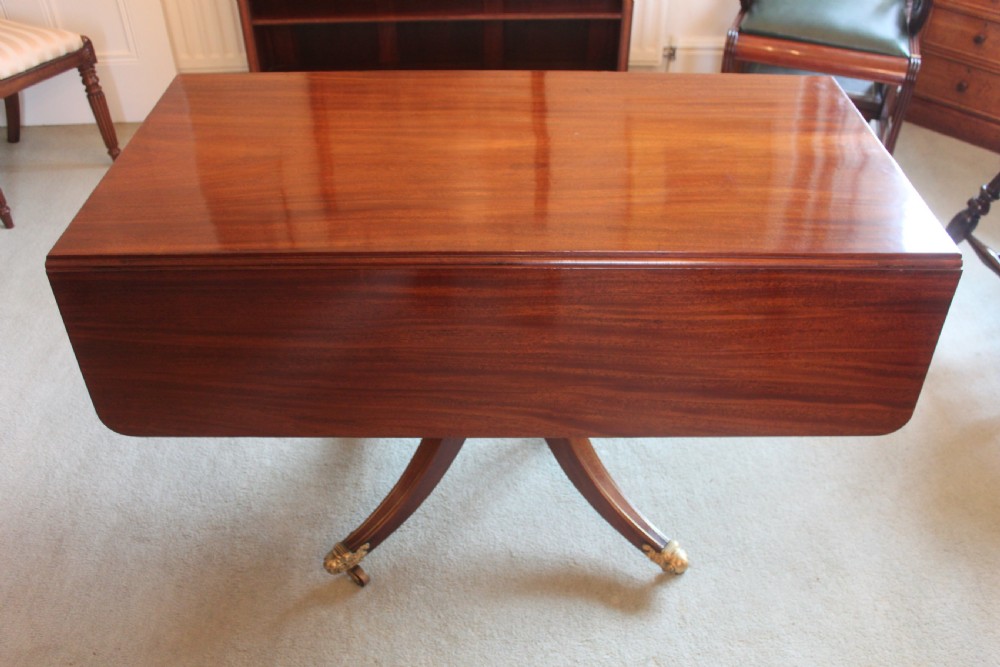 A dark mahogany Regency Pembroke table featuring brass line inlay, a single end drawer, drop leaves, and quadform sabre legs with brass cap castors. View VI