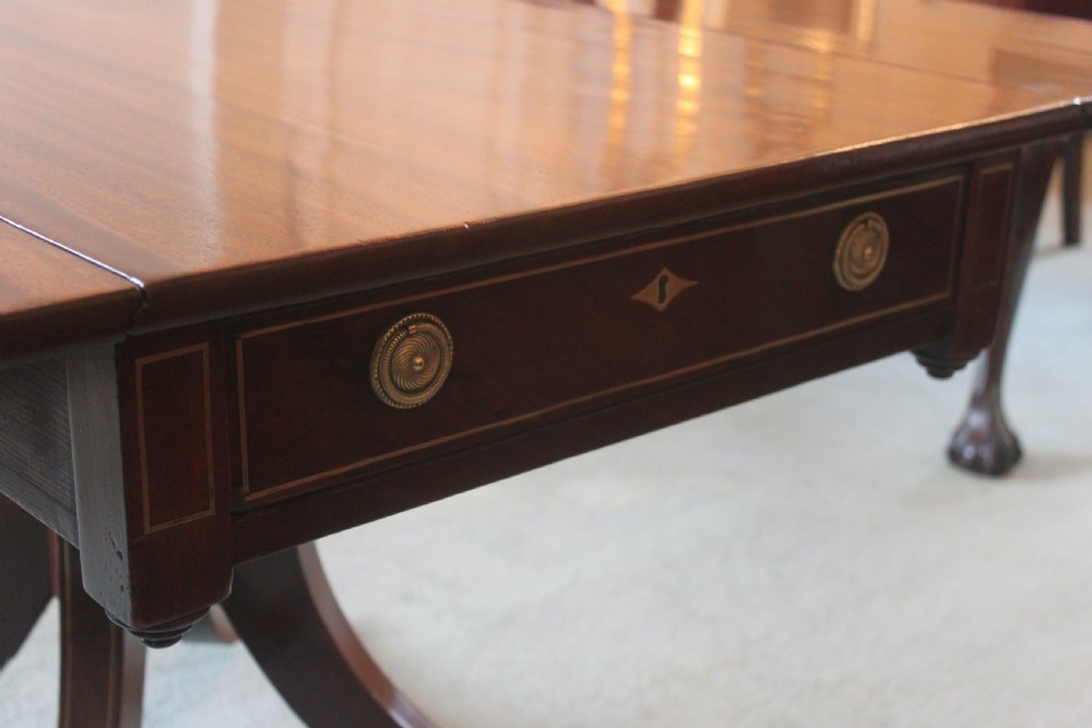 A dark mahogany Regency Pembroke table featuring brass line inlay, a single end drawer, drop leaves, and quadform sabre legs with brass cap castors. View XI