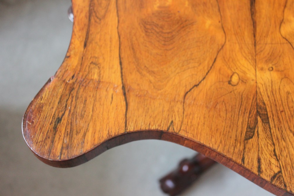 A Victorian rosewood foldover tea table featuring a serpentine front, carved pedestal stem, and quad-form cabriole legs. View VIII
