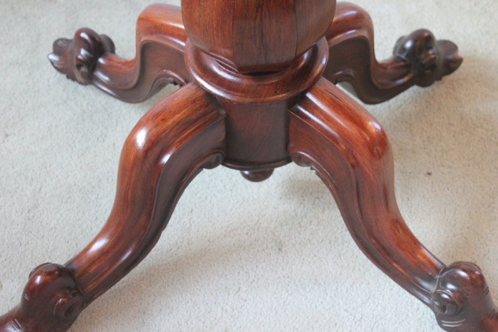 A Victorian rosewood foldover tea table featuring a serpentine front, carved pedestal stem, and quad-form cabriole legs. View IX