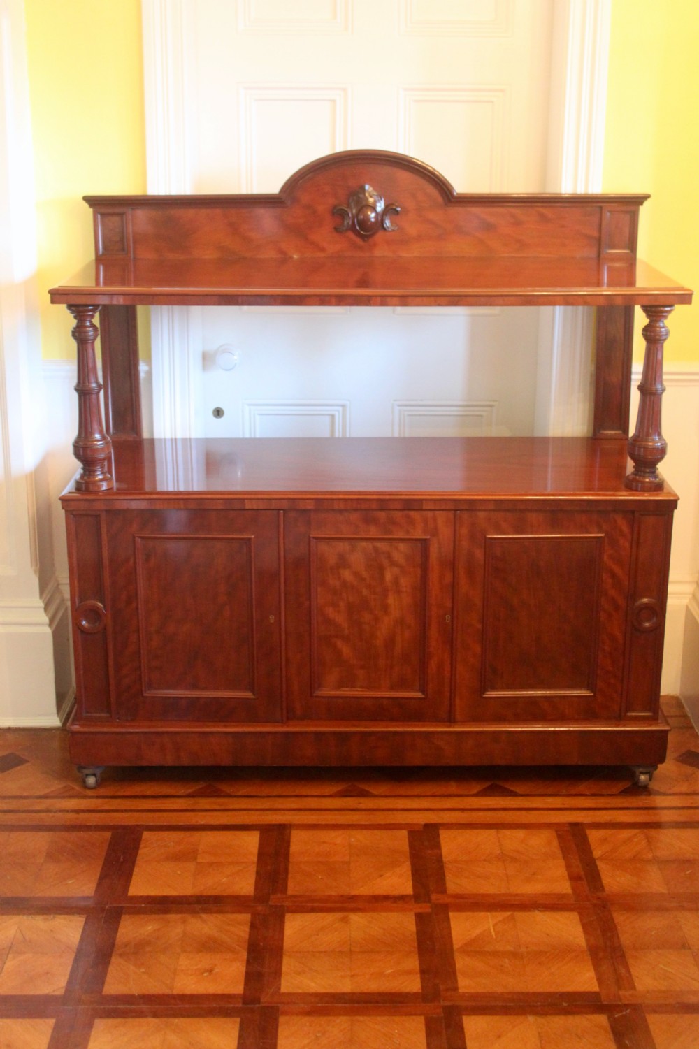 Victorian mahogany buffet sideboard featuring a raised upper tier supported by turned columns above a three-door cupboard base.