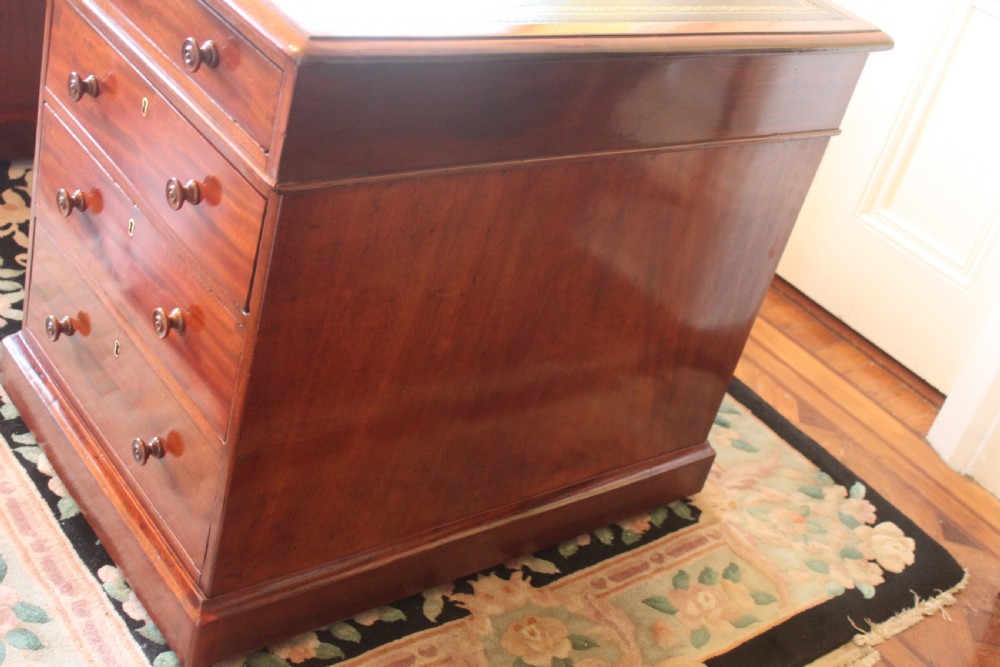An early 19th-century mahogany pedestal desk featuring a dark green leather writing top, nine drawers with turned wooden knobs, and a plinth base. View VIII