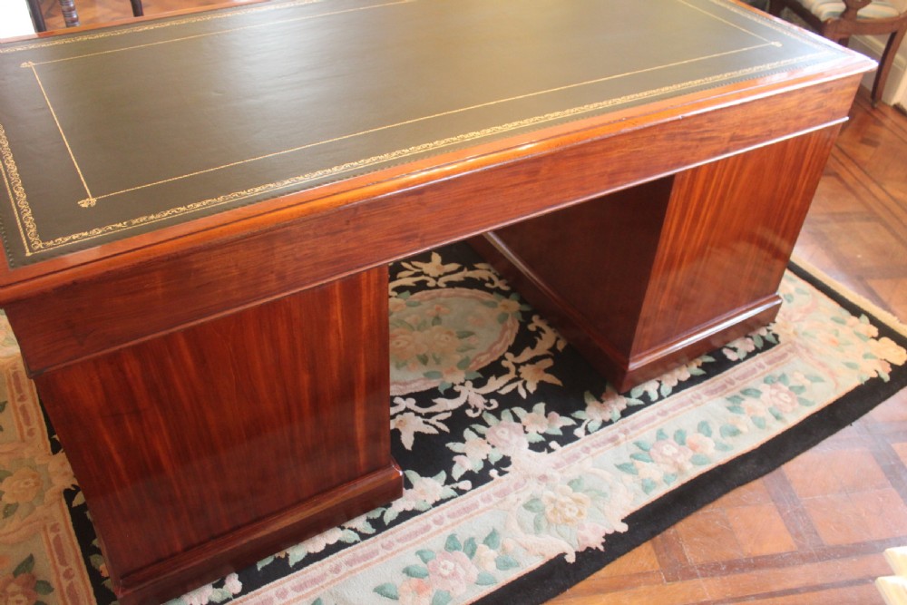 An early 19th-century mahogany pedestal desk featuring a dark green leather writing top, nine drawers with turned wooden knobs, and a plinth base. View XIV