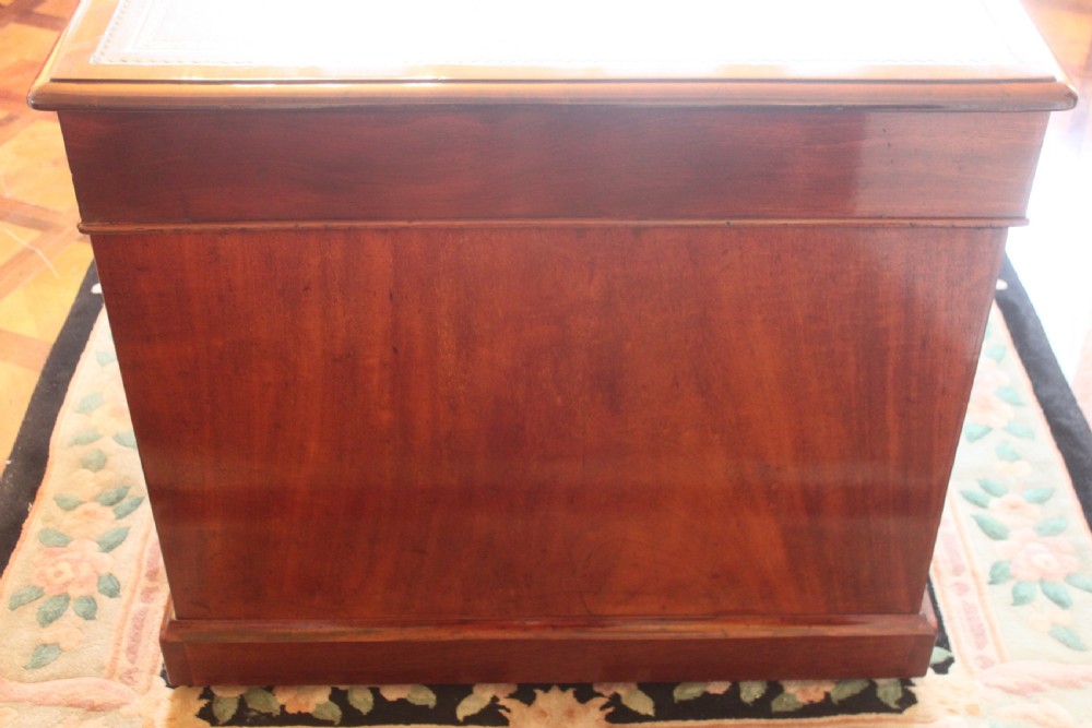 An early 19th-century mahogany pedestal desk featuring a dark green leather writing top, nine drawers with turned wooden knobs, and a plinth base. View XV
