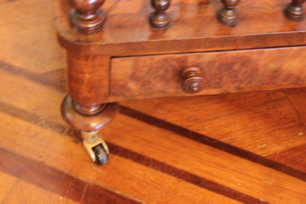 A Victorian burr walnut Canterbury what-not featuring a flat top surface with a gallery rail, turned spindle supports, a slatted middle partition section, a single base drawer, and turned legs with brass castors. View VIII