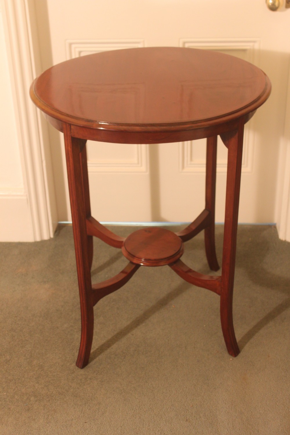 An Edwardian mahogany circular occasional table featuring slender curved legs connected by an X-shaped cross-stretcher with a small circular central under-tier. View II