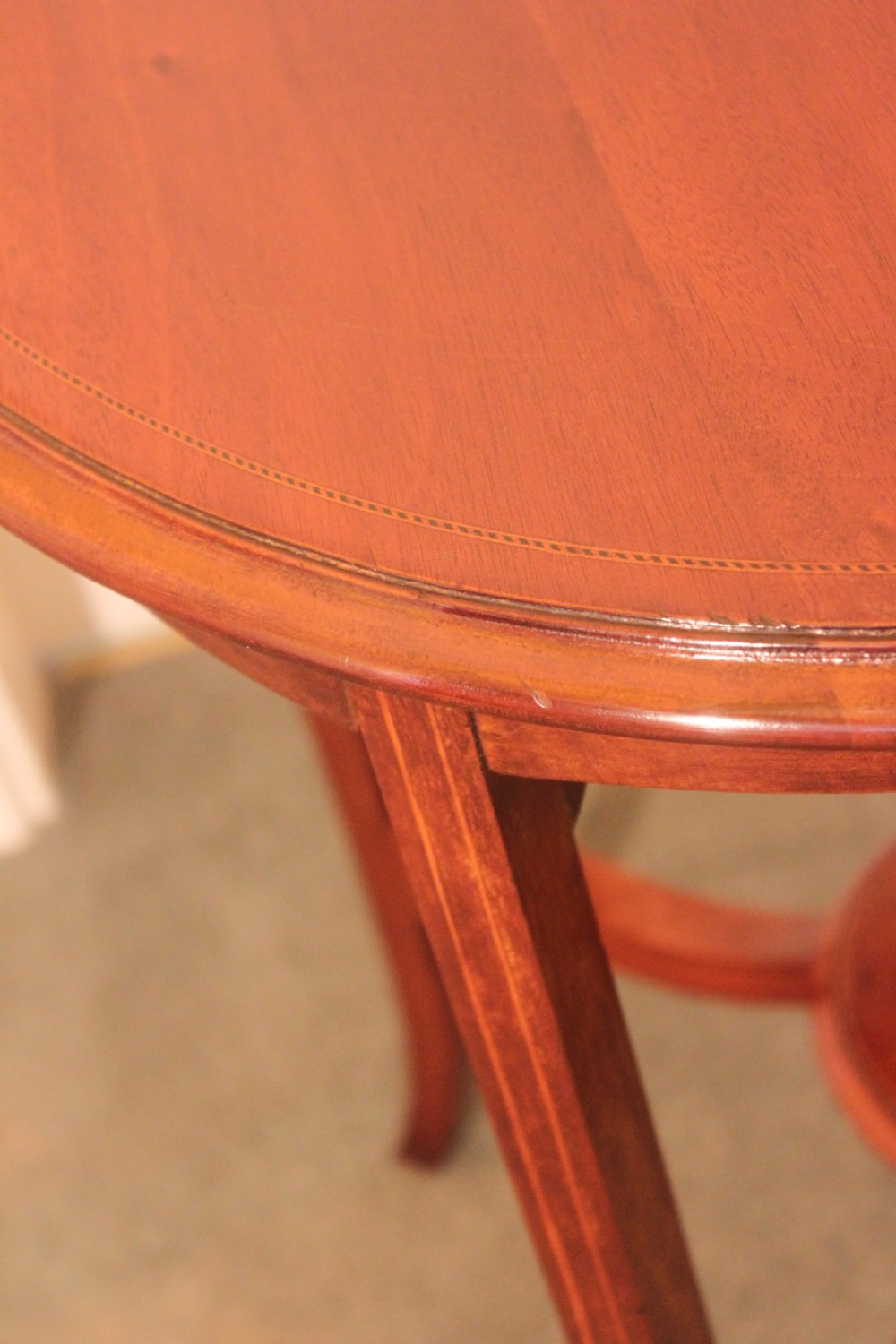 An Edwardian mahogany circular occasional table featuring slender curved legs connected by an X-shaped cross-stretcher with a small circular central under-tier. View III