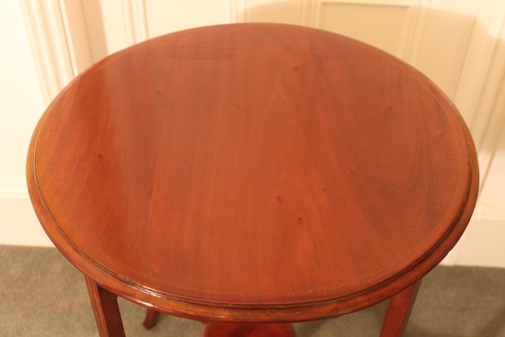 An Edwardian mahogany circular occasional table featuring slender curved legs connected by an X-shaped cross-stretcher with a small circular central under-tier. View V