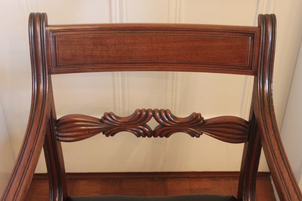 An antique Regency mahogany desk chair featuring sweeping reeded arms, a carved central back rail, and a black leather seat. View VI