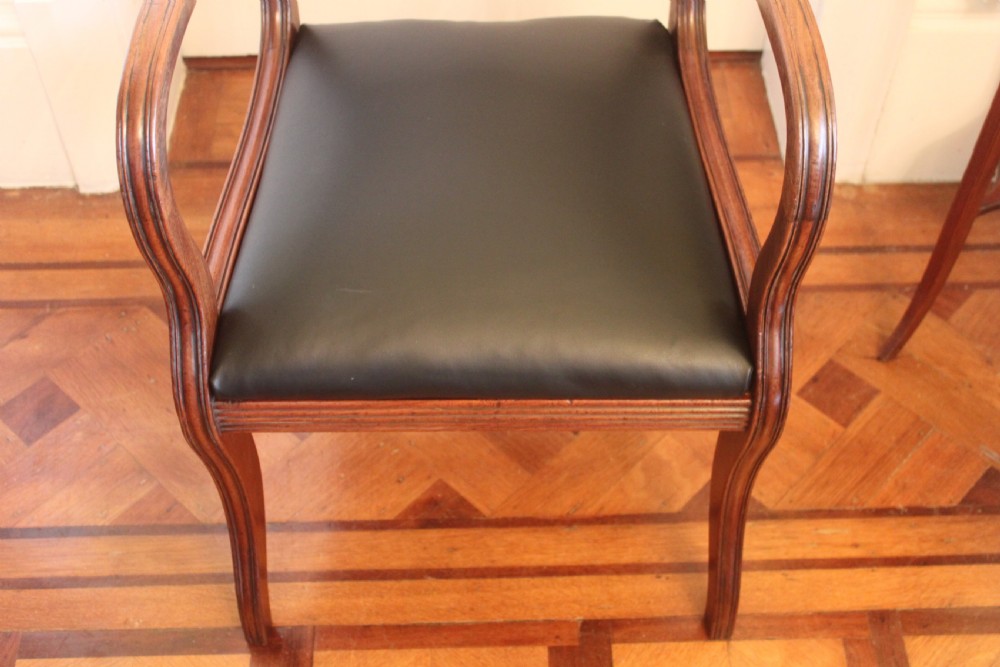An antique Regency mahogany desk chair featuring sweeping reeded arms, a carved central back rail, and a black leather seat. View VII