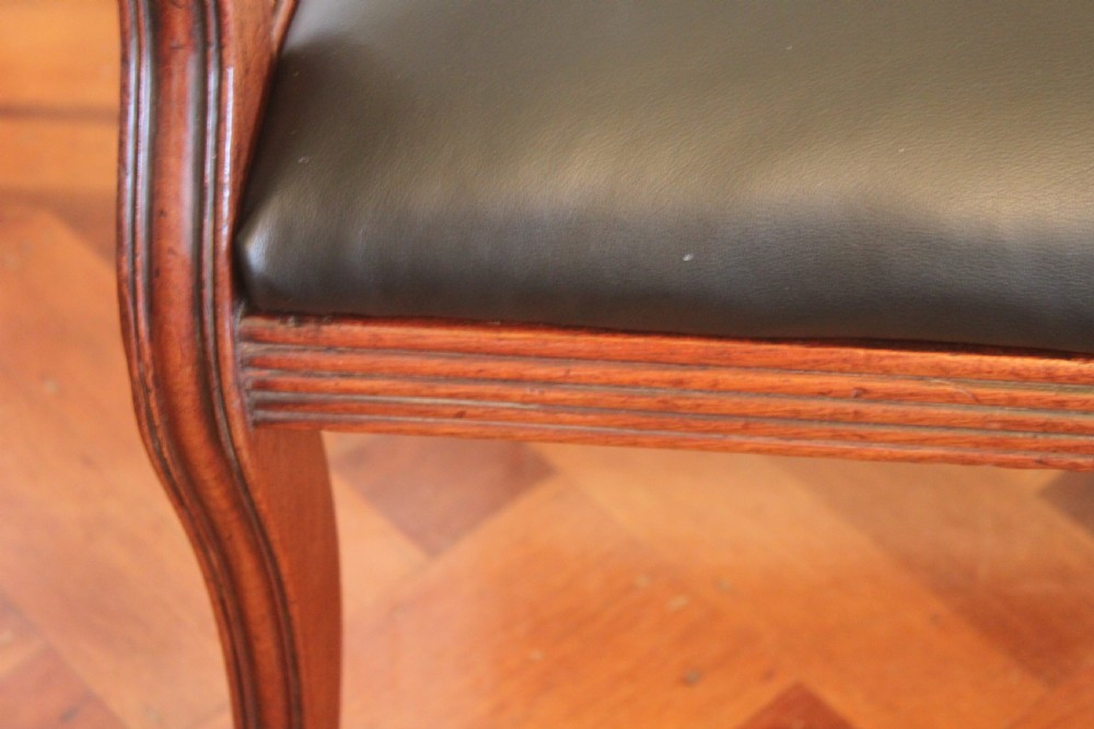 An antique Regency mahogany desk chair featuring sweeping reeded arms, a carved central back rail, and a black leather seat. View VIII