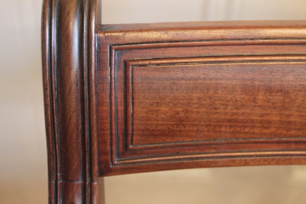 An antique Regency mahogany desk chair featuring sweeping reeded arms, a carved central back rail, and a black leather seat. View IX