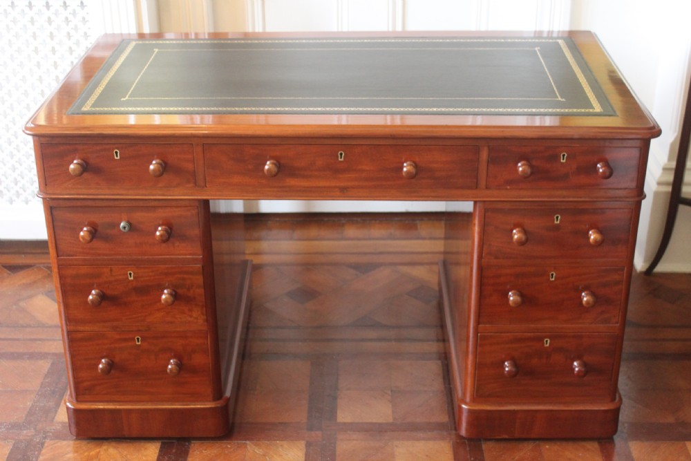 Victorian mahogany pedestal desk with a dark green leather inset top and nine drawers with turned handles.