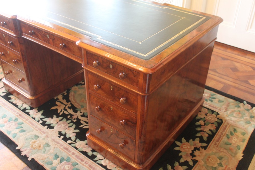 A Victorian burr walnut partners desk with a green leather inset writing top, twin pedestals containing multiple drawers with turned wooden handles, resting on plinth bases. View II