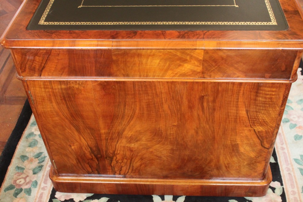 A Victorian burr walnut partners desk with a green leather inset writing top, twin pedestals containing multiple drawers with turned wooden handles, resting on plinth bases. View V