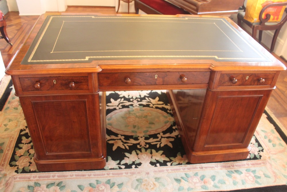 A Victorian burr walnut partners desk with a green leather inset writing top, twin pedestals containing multiple drawers with turned wooden handles, resting on plinth bases. View VII