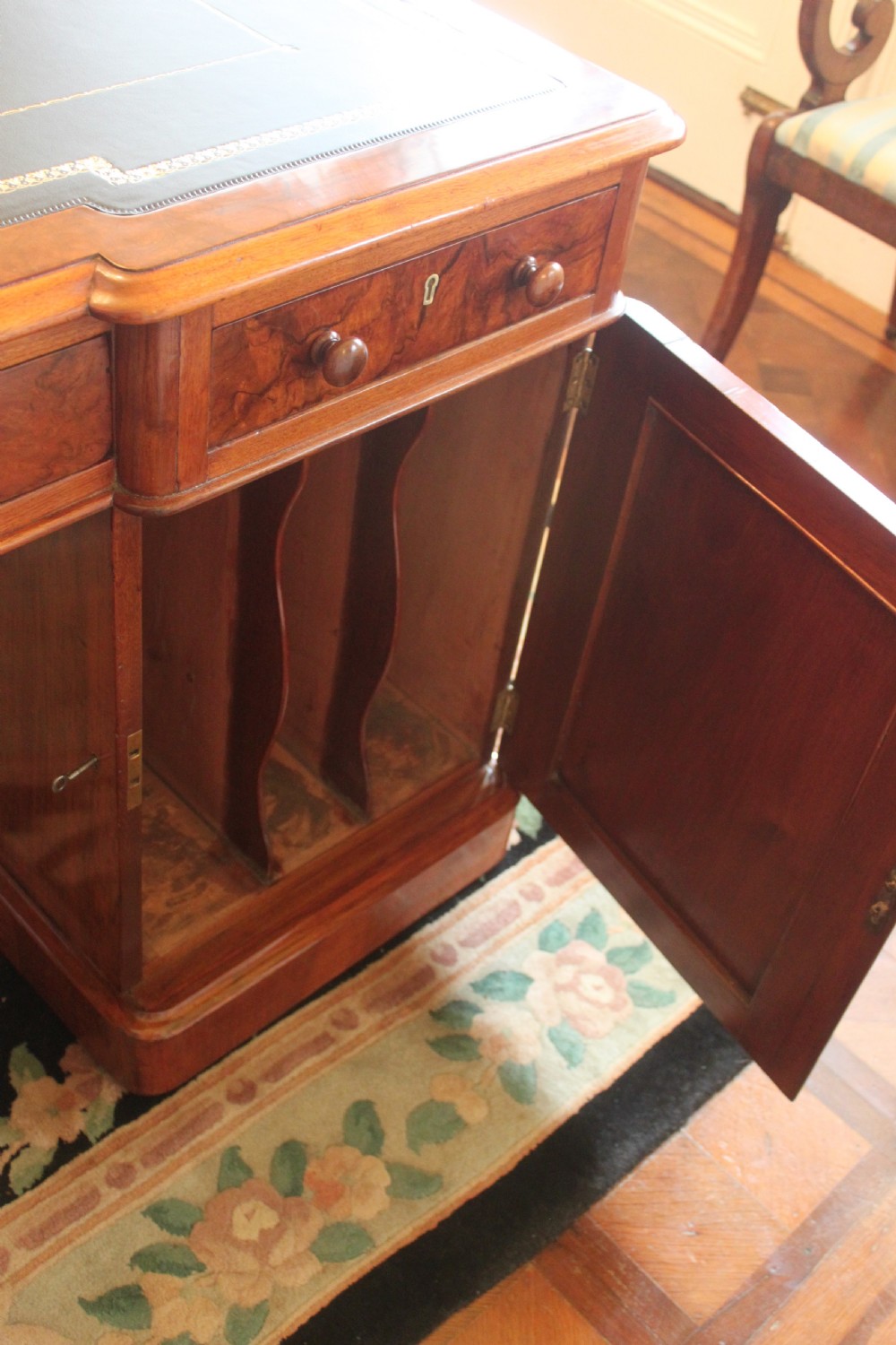 A Victorian burr walnut partners desk with a green leather inset writing top, twin pedestals containing multiple drawers with turned wooden handles, resting on plinth bases. View VIII