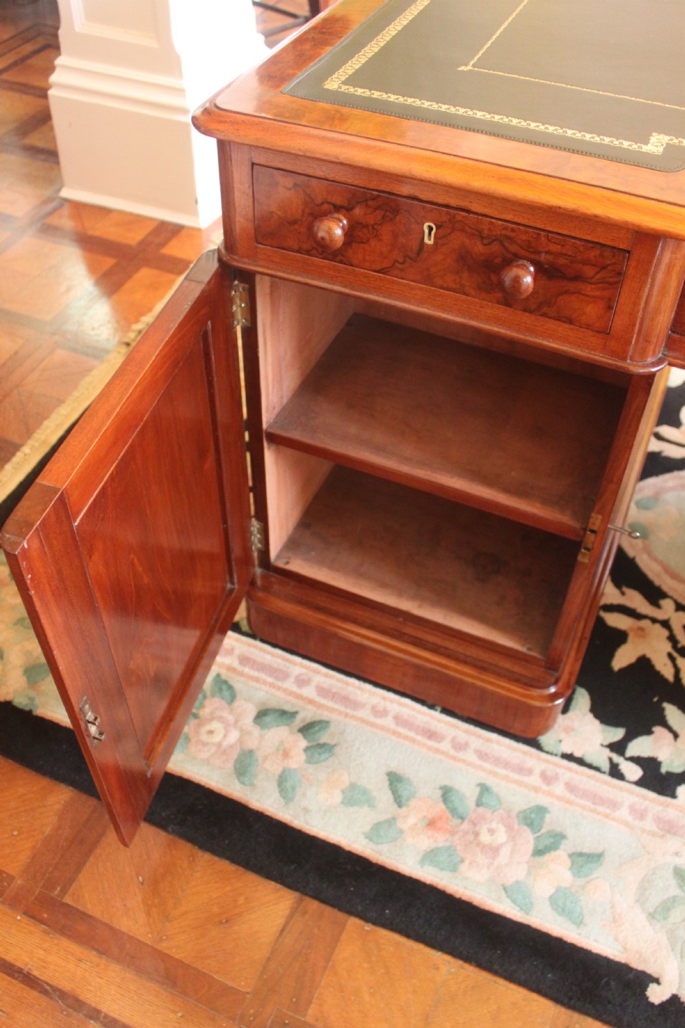 A Victorian burr walnut partners desk with a green leather inset writing top, twin pedestals containing multiple drawers with turned wooden handles, resting on plinth bases. View IX