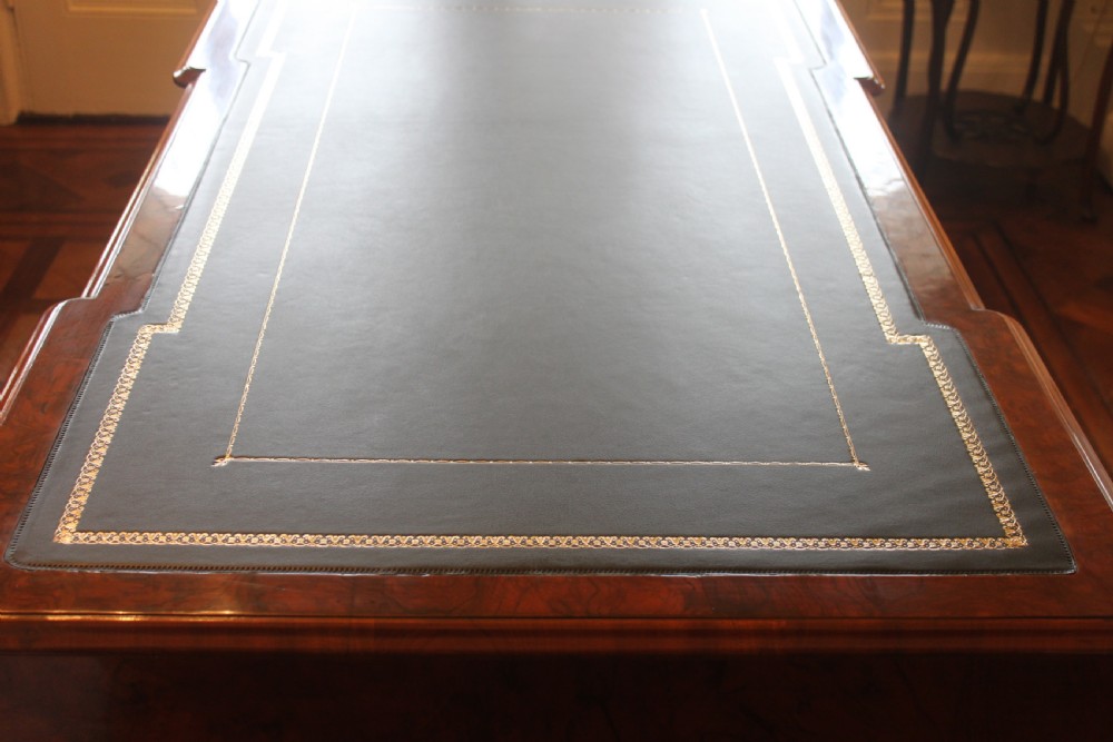 A Victorian burr walnut partners desk with a green leather inset writing top, twin pedestals containing multiple drawers with turned wooden handles, resting on plinth bases. View XI