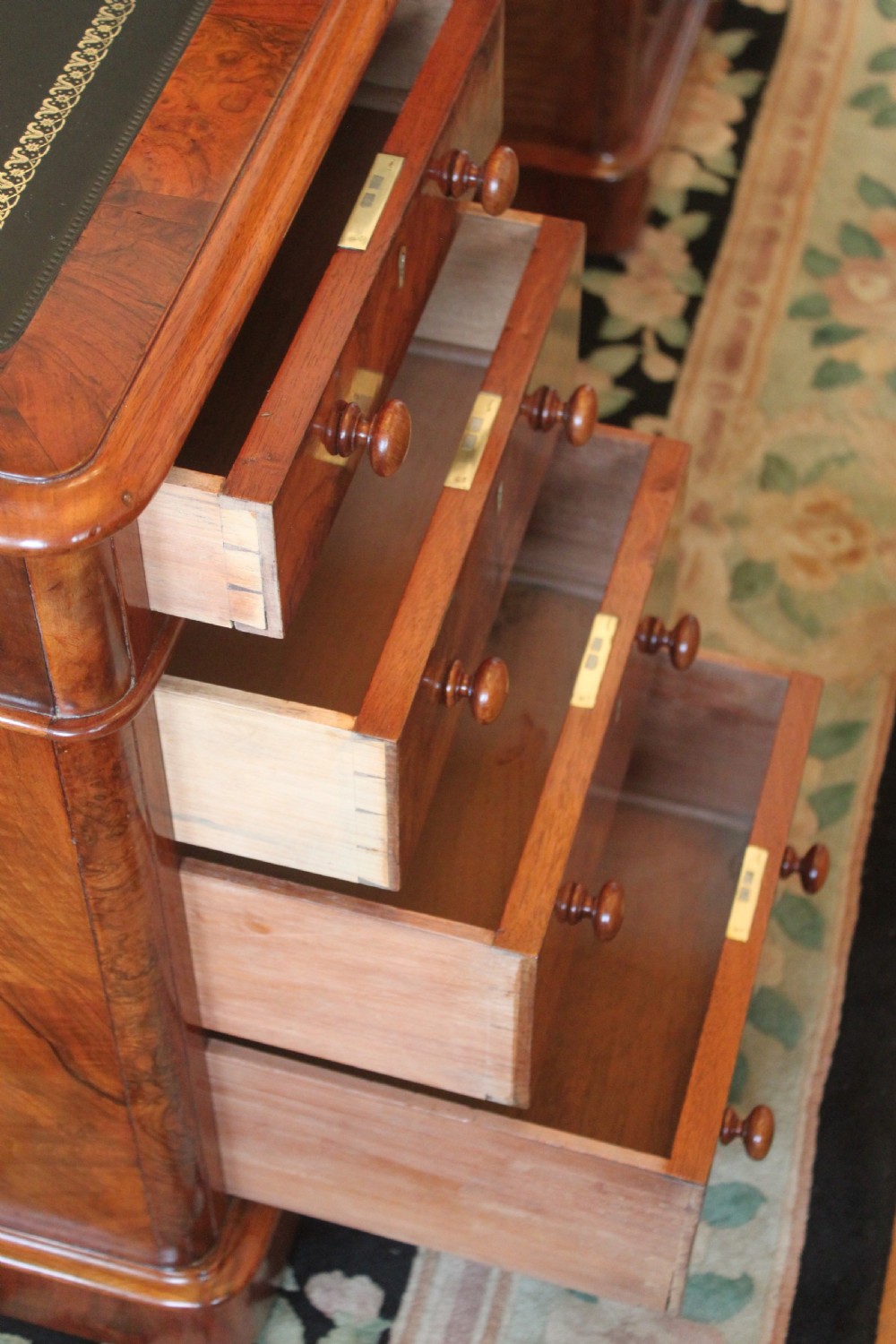 A Victorian burr walnut partners desk with a green leather inset writing top, twin pedestals containing multiple drawers with turned wooden handles, resting on plinth bases. View XIII