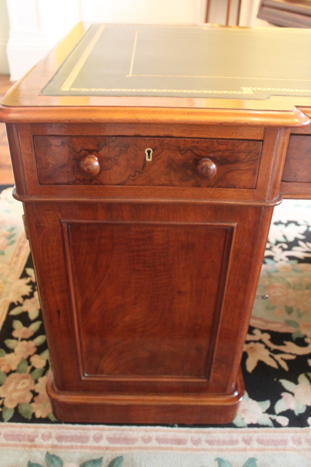 A Victorian burr walnut partners desk with a green leather inset writing top, twin pedestals containing multiple drawers with turned wooden handles, resting on plinth bases. View XVII