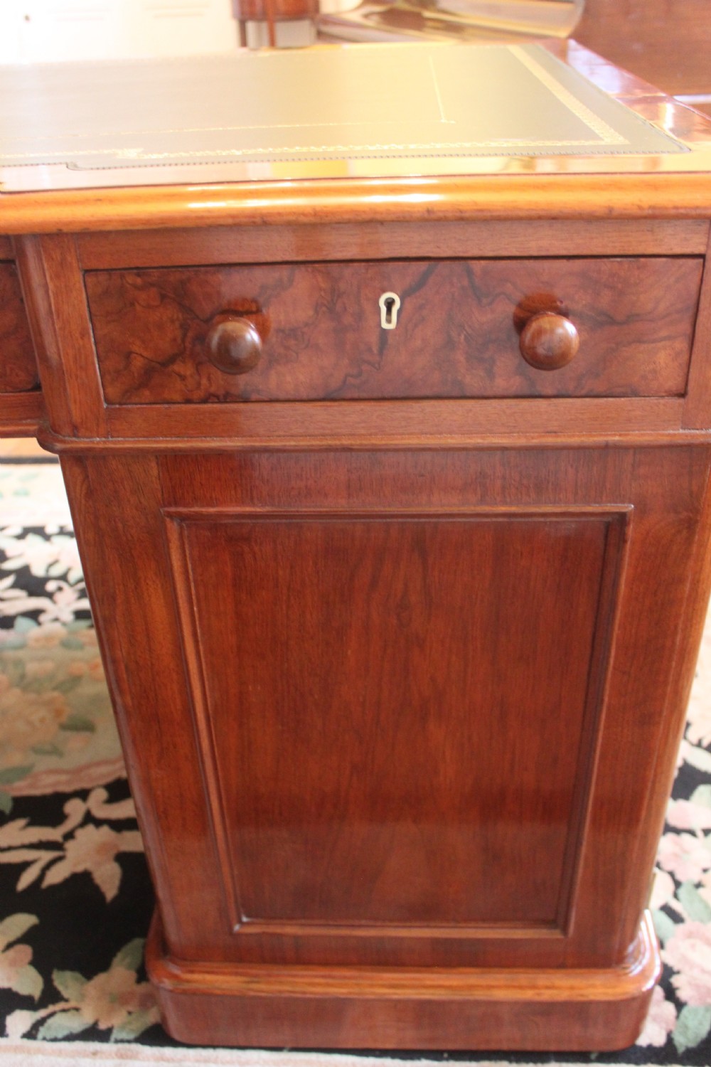 A Victorian burr walnut partners desk with a green leather inset writing top, twin pedestals containing multiple drawers with turned wooden handles, resting on plinth bases. View XVIII