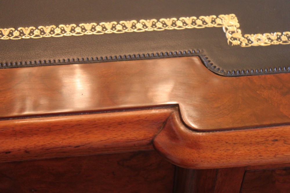A Victorian burr walnut partners desk with a green leather inset writing top, twin pedestals containing multiple drawers with turned wooden handles, resting on plinth bases. View XIX