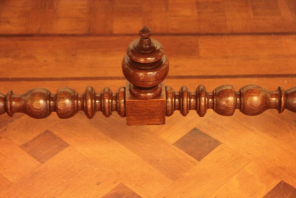 An antique French oak writing desk featuring a gold-tooled dark leather top insert, frieze drawers, turned baluster legs, and a stretcher base with a central finial. View VII